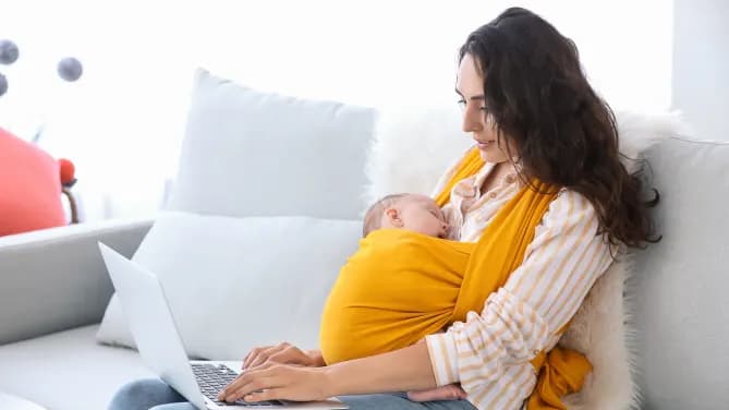 woman with newborn baby while on her laptop