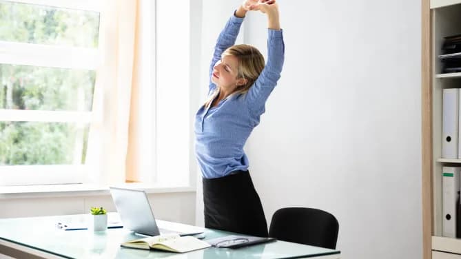 woman standing and stretching at a desk