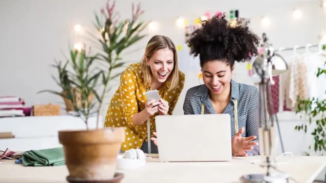 Two coworkers in front of a laptop. Photo courtesy of AdobeStock.