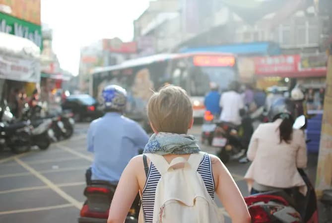 Person in backpack looking at busy street 