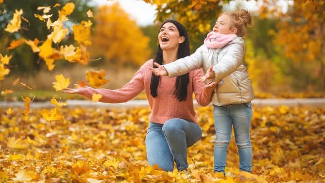 perfect mom playing in the leaves with her daughter