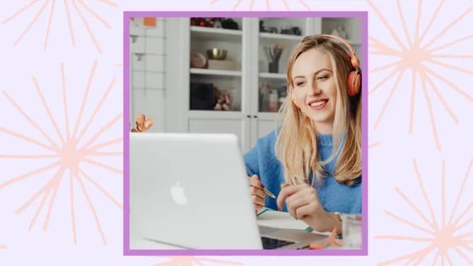 woman smiling working on laptop with headphones on.