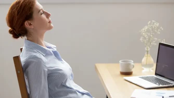 woman sitting with eyes closed meditating at her desk