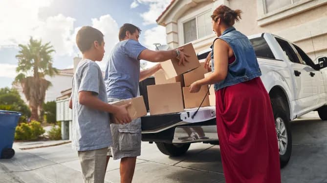 family unloading pickup truck and moving into new house