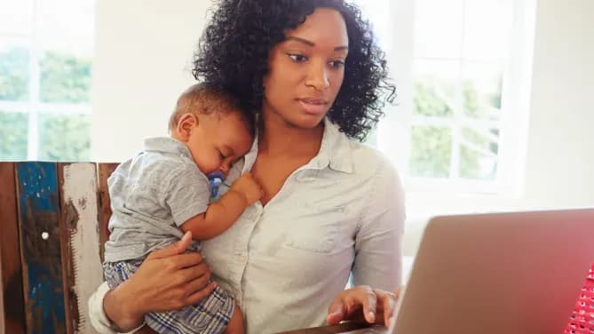 mother holding baby and on laptop