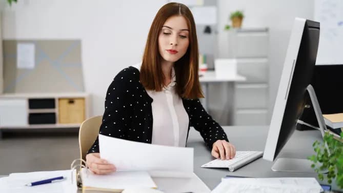 Woman reviewing papers at computer