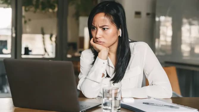 Woman looking surprised at open laptop in front of her.