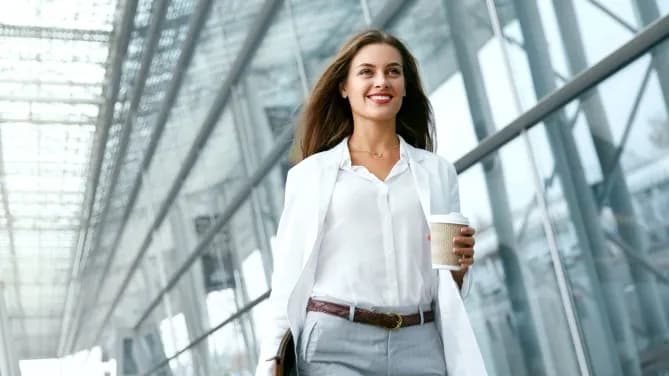 woman walking out of work with coffee in hand