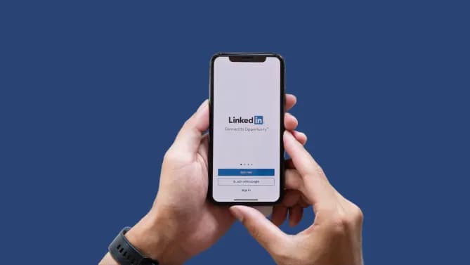Hands holding phone, phone has LinkedIn on the screen