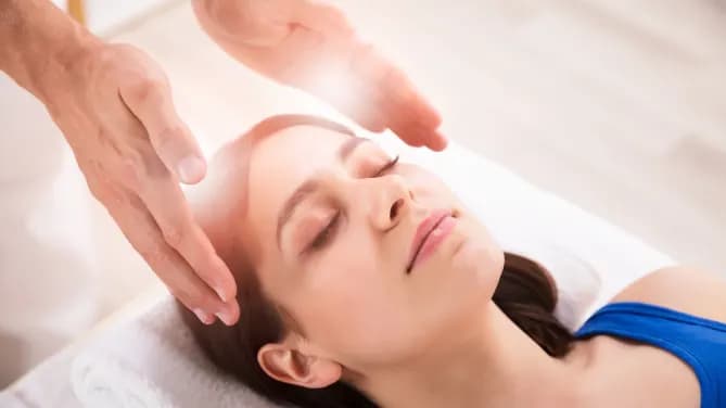 woman lying on massage table undergoing reiki session