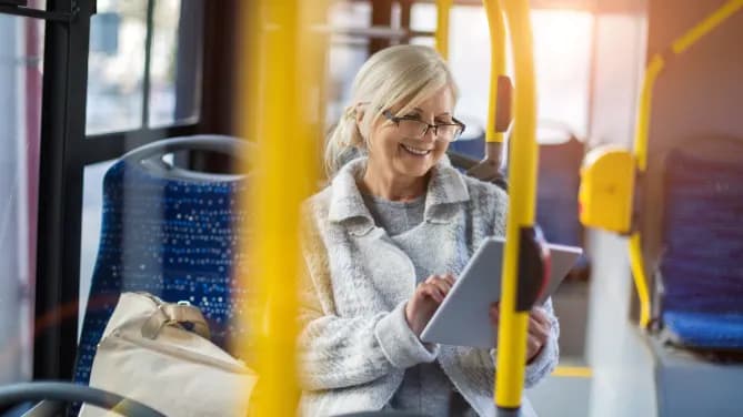 older woman on tablet commuting to work