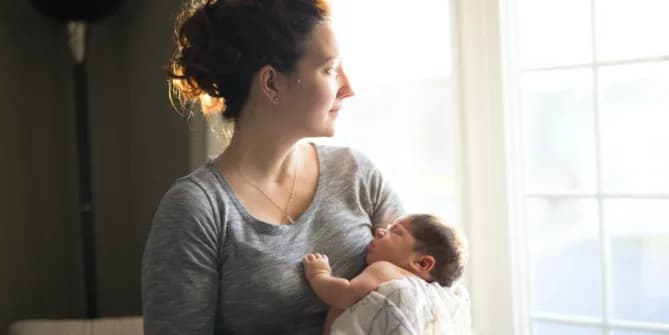 Pensive woman holding baby