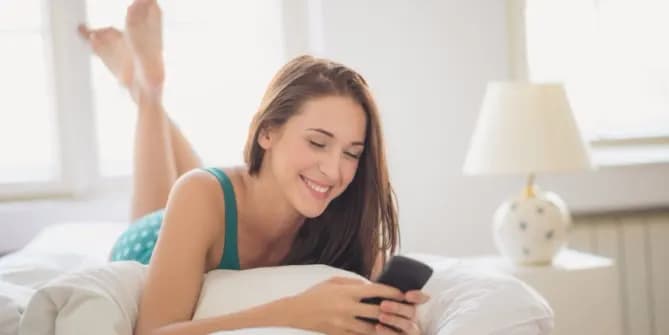 Woman looking at phone on bed