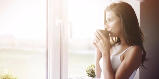 Woman drinking coffee and looking out window