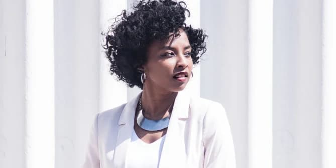Black woman in a white suit looking off to the side