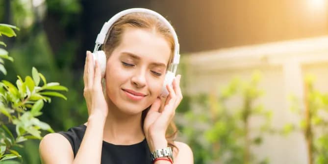 A woman smiles with her eyes closed while listening to music 