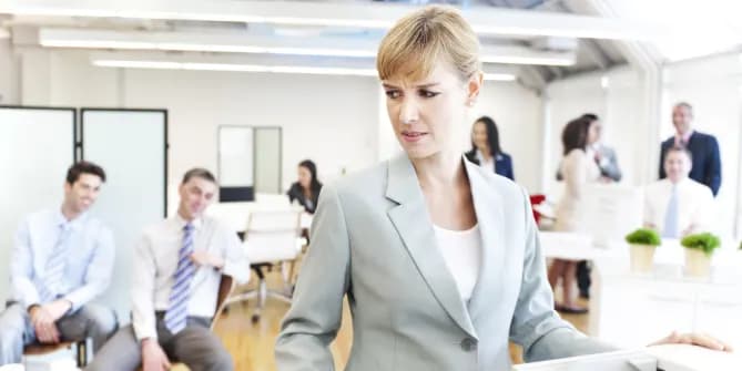 woman looking uncomfortable as male colleagues look on